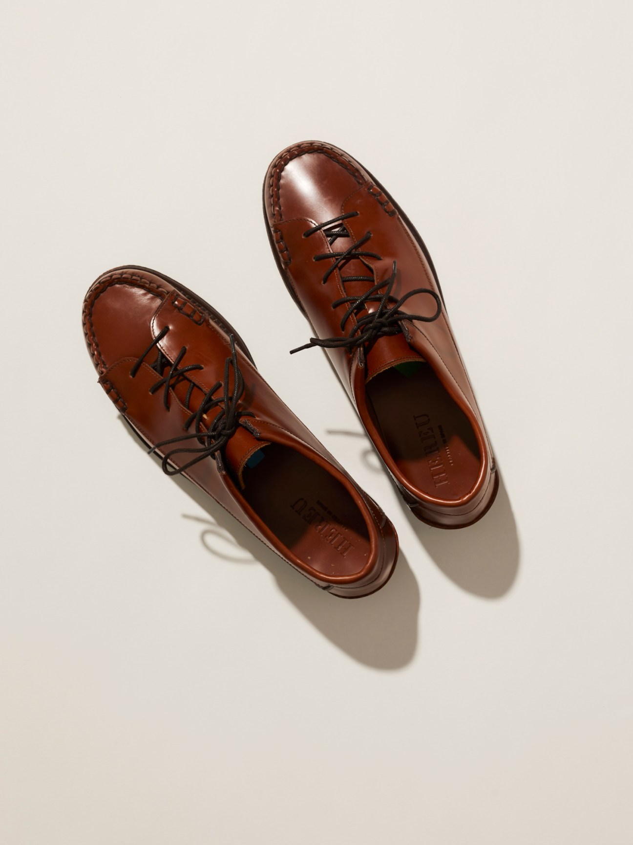 Pair of brown leather lace-up moccasin shoes by Hereu, shown from above on a neutral background.