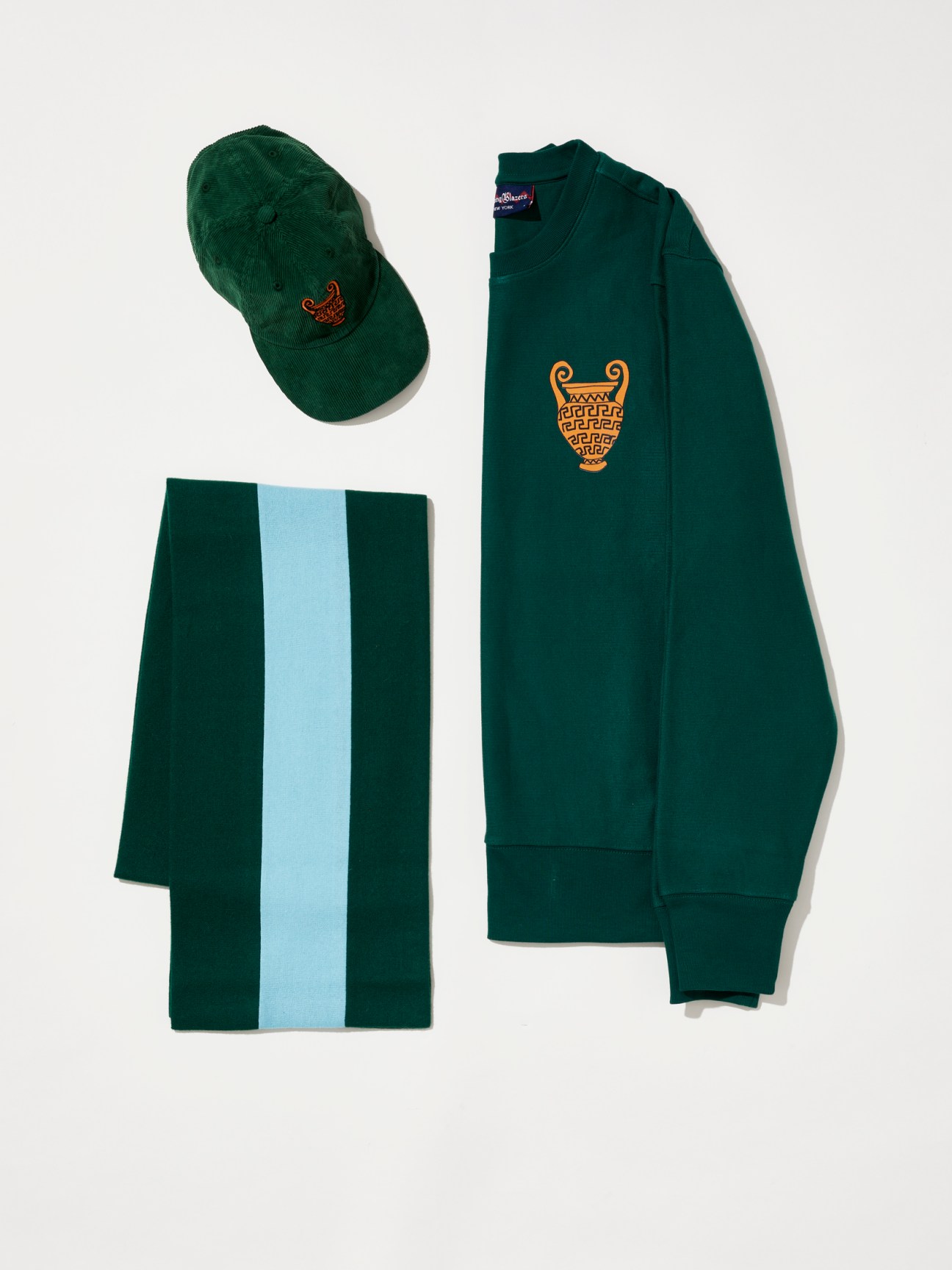 Green corduroy cap, striped scarf, and sweatshirt with Greek amphora embroidery by Rowing Blazers x Luke Edward Hall