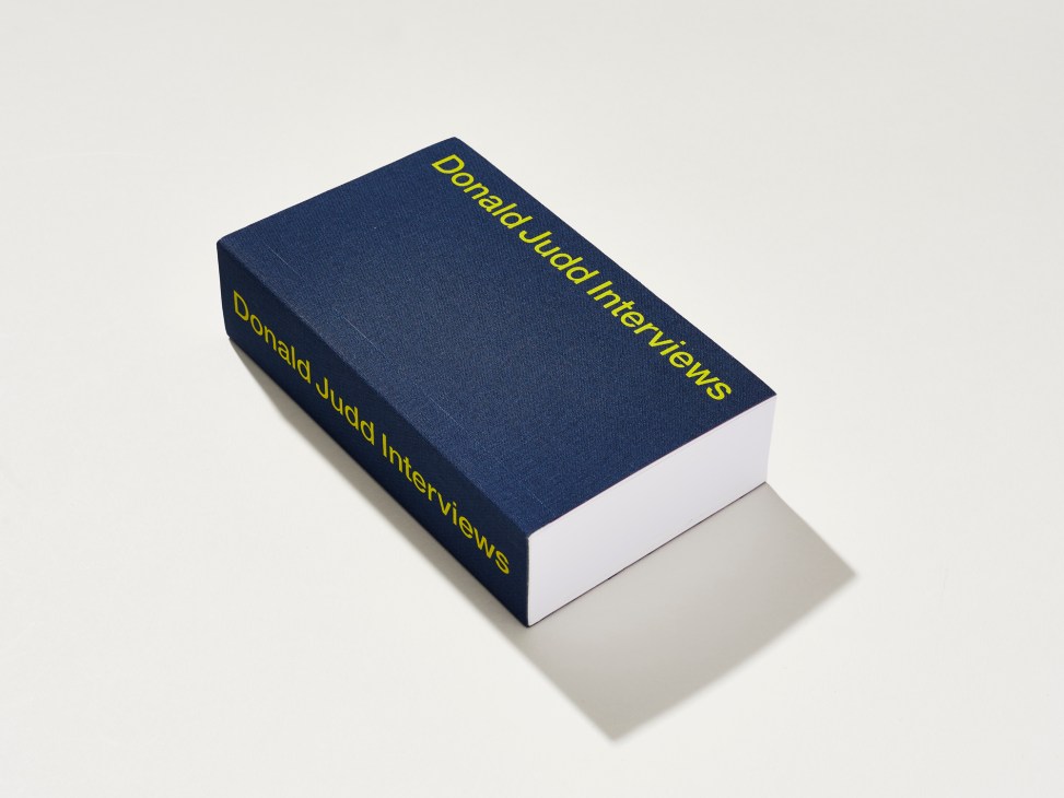 Navy blue hardcover book titled 'Donald Judd Interviews' with yellow text on a white background.