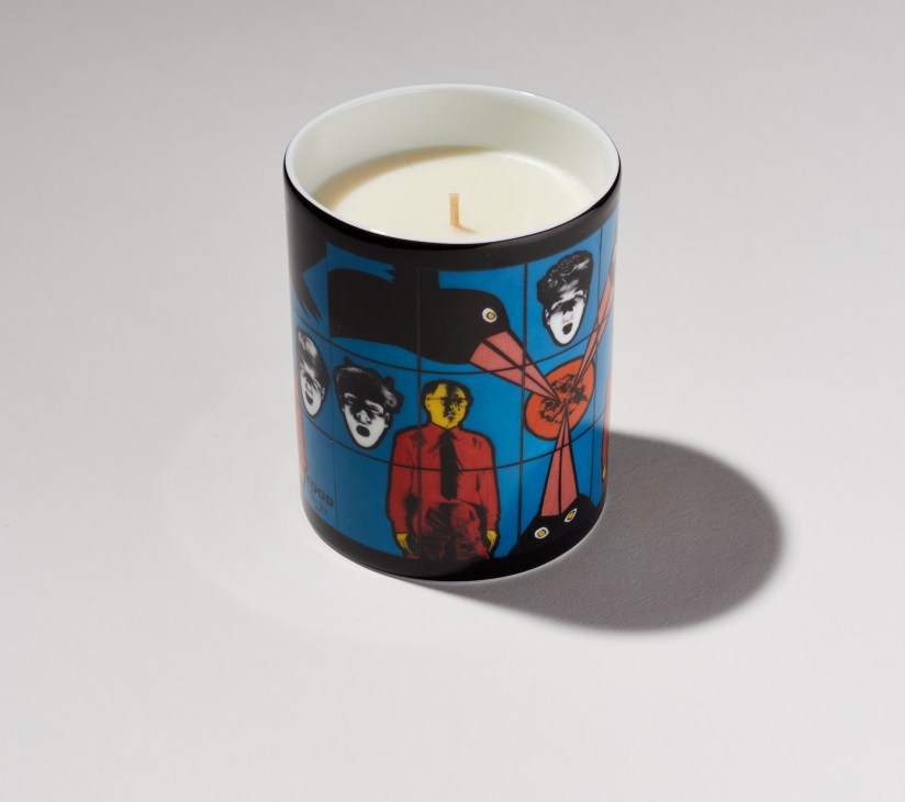Gilbert & George candle with white wax and cream-colored label featuring colorful pop art portraits on blue background.