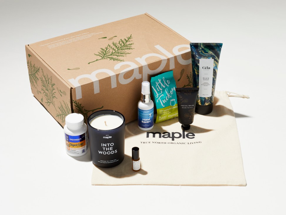 Maple magazine subscription box with natural beauty products including candles, skincare, and plant-based items displayed on white paper.