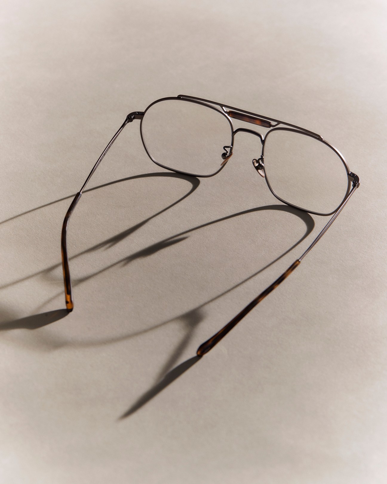 Giorgio Armani aviator sunglasses with metal frames and tinted lenses casting shadows on neutral background