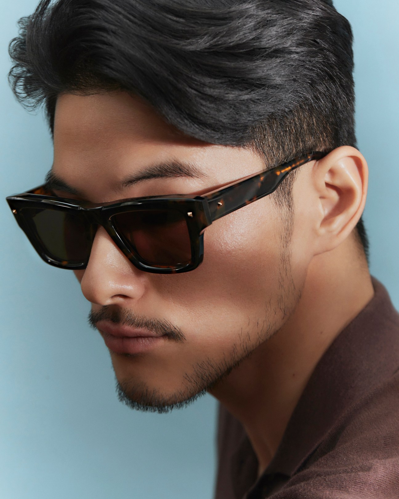 Man in profile wearing dark tortoiseshell Valentino sunglasses with styled hair and facial stubble
