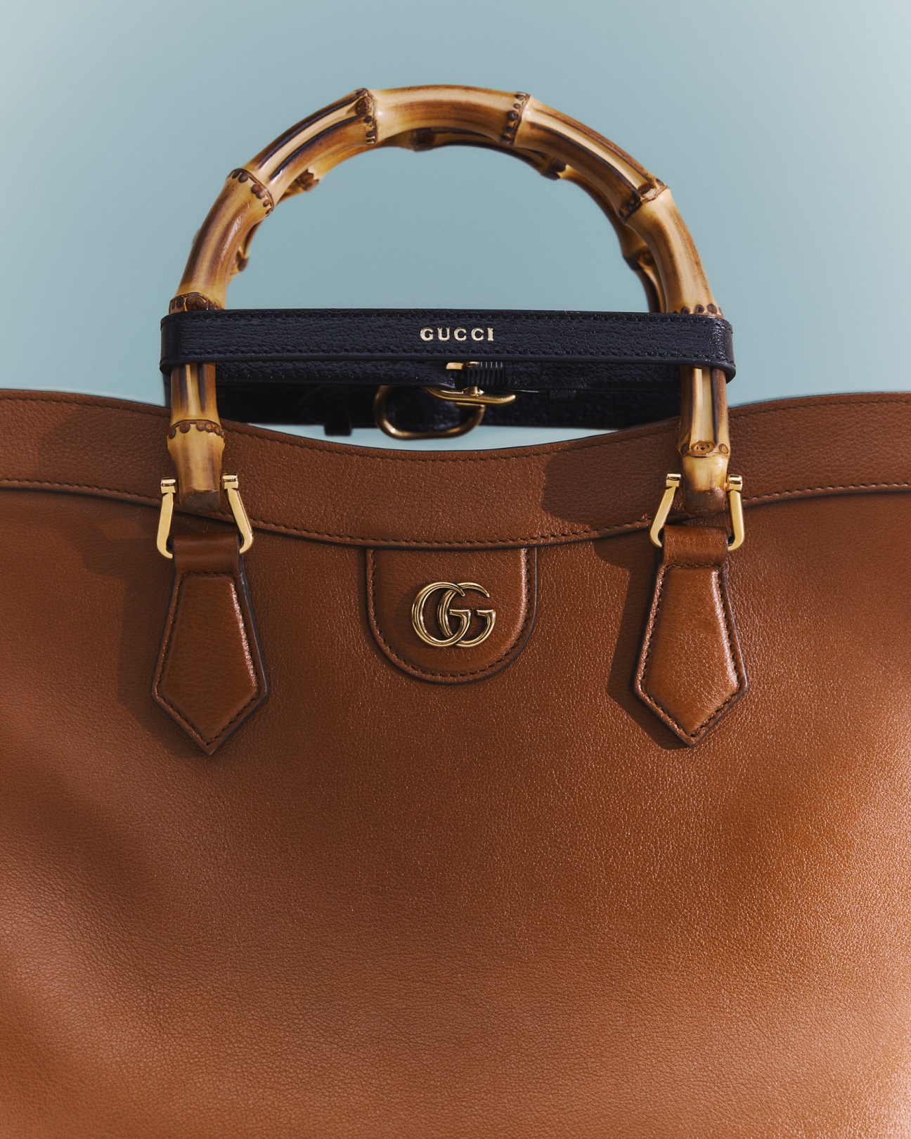 Brown leather Gucci handbag with bamboo handle and gold hardware featuring the iconic GG logo