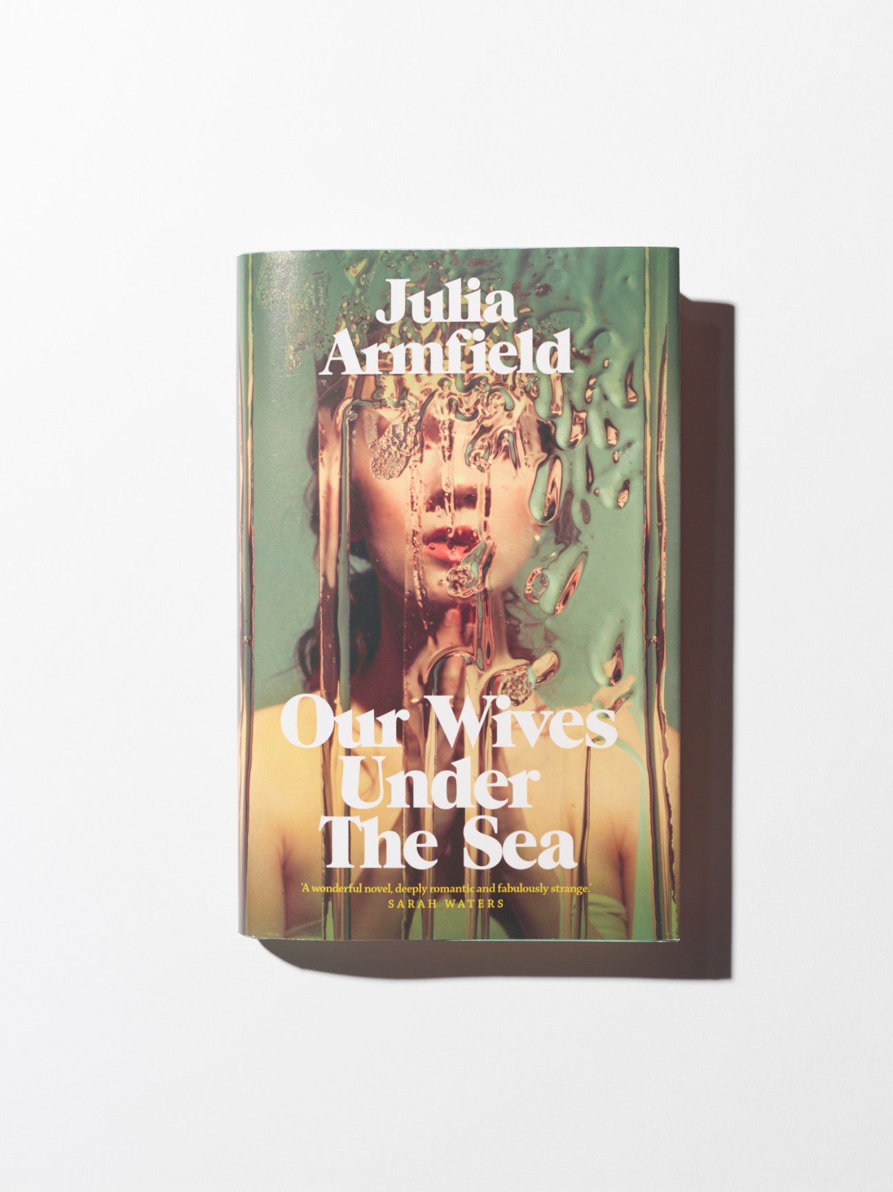 Book cover of Our Wives Under the Sea by Julia Armfield showing a woman's face distorted through water or glass