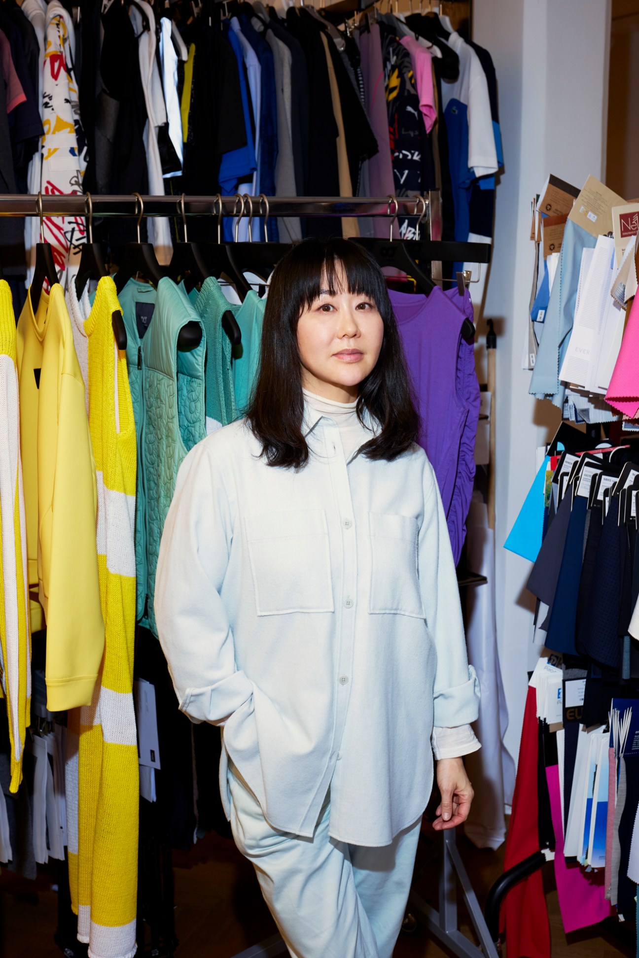 Kyong Yeom standing in front of clothing shelf