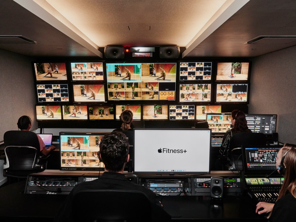 Television production control room with multiple monitors showing fitness workout footage and Apple Fitness+ branding