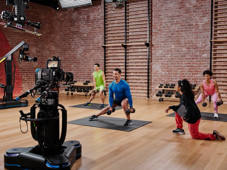 Fitness trainers exercising in Apple Fitness+ studio with professional cameras and lighting equipment