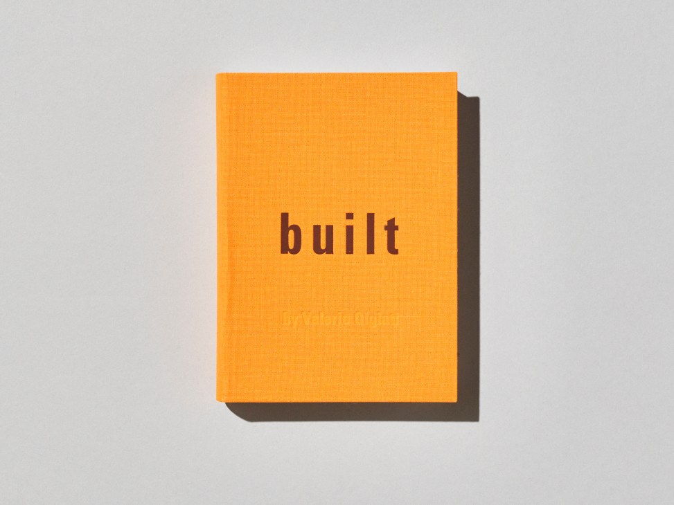 Orange book cover with the word 'built' in dark text and 'by park, switzerland' below, casting shadow on white surface