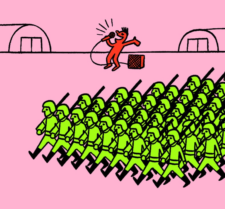 Red figure with microphone performing on stage above rows of green uniformed soldiers with rifles in formation