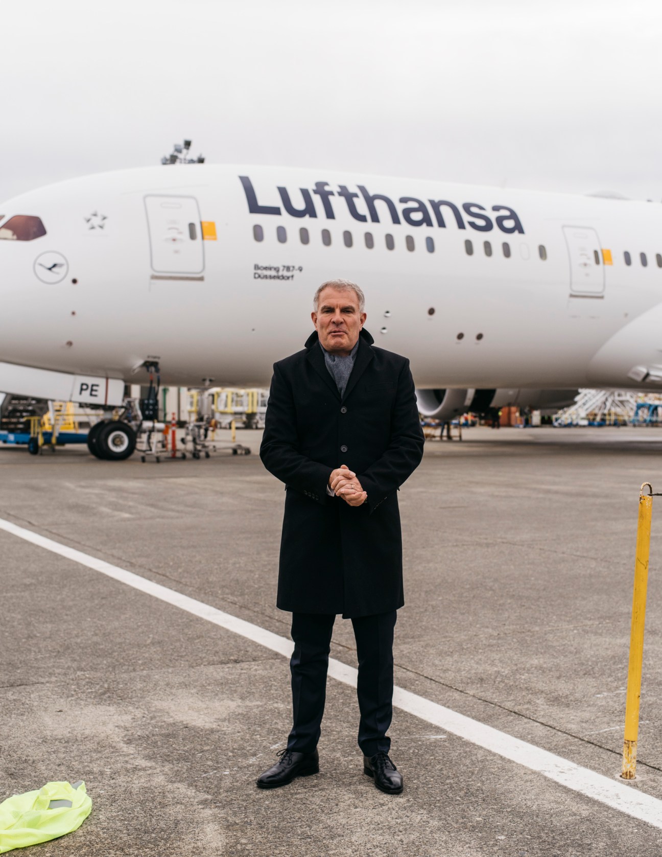 Lufthansa CEO Carsten Spohr standing on airport tarmac in front of white Lufthansa Boeing 787-9 aircraft