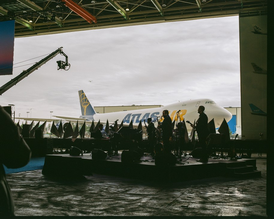 Silhouettes of people watching Atlas Air's final Boeing 747 cargo plane parked outside Boeing's Everett factory hangar