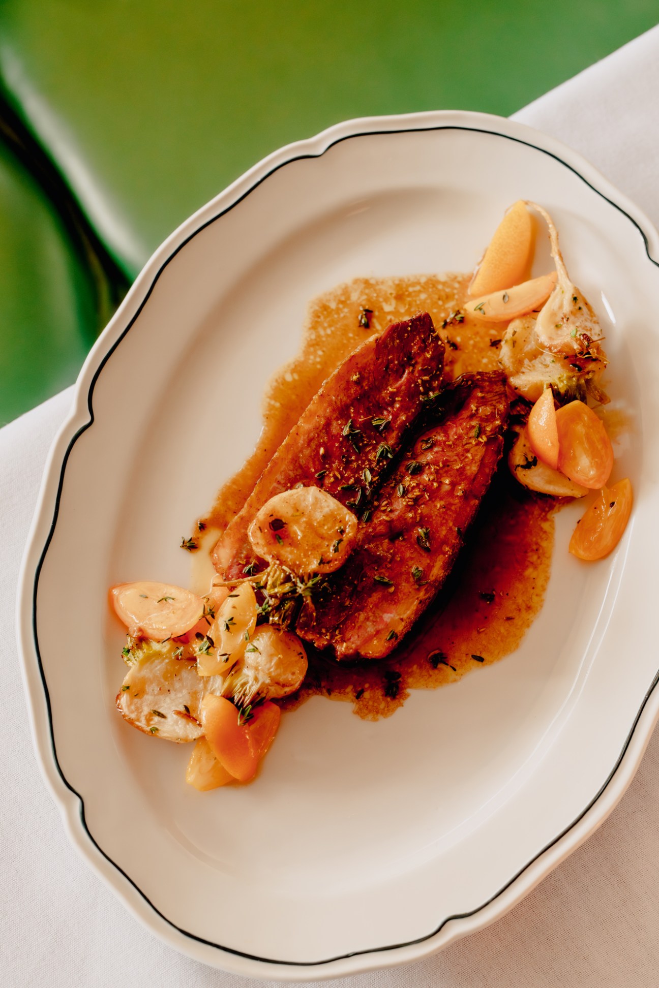 Pan-seared fish fillet with sautéed mushrooms and herbs on white scalloped plate