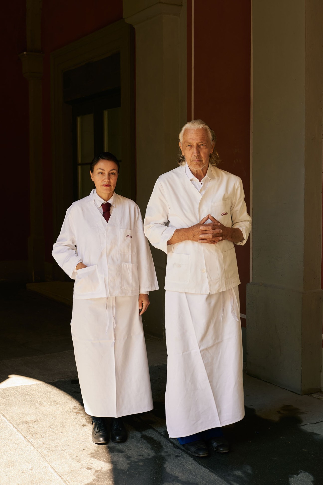 Two people in white bartender jackets standing in doorway at Schumann's Bar Munich