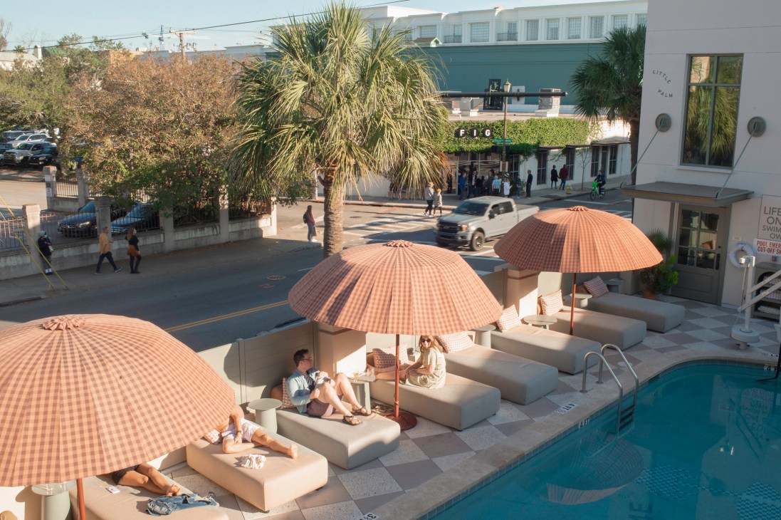 Poolside lounge area with orange striped umbrellas and beige seating at The Ryder hotel