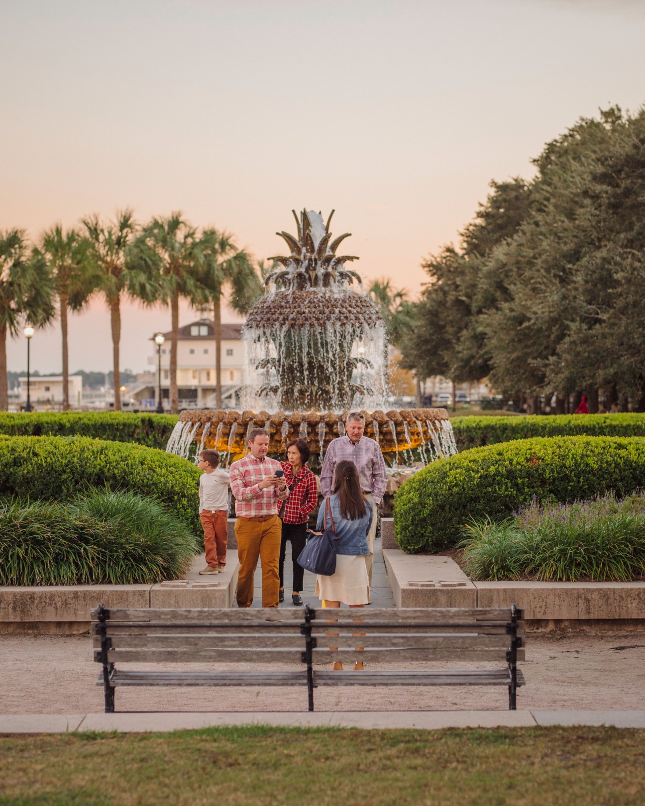 A family poses together in front of the iconic Pineapple Fountain in Charleston's Waterfront Park at sunset
