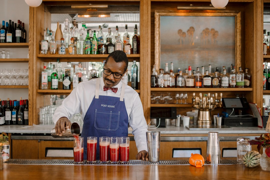 Bartender in bow tie and apron preparing red cocktails at The Post House Inn bar