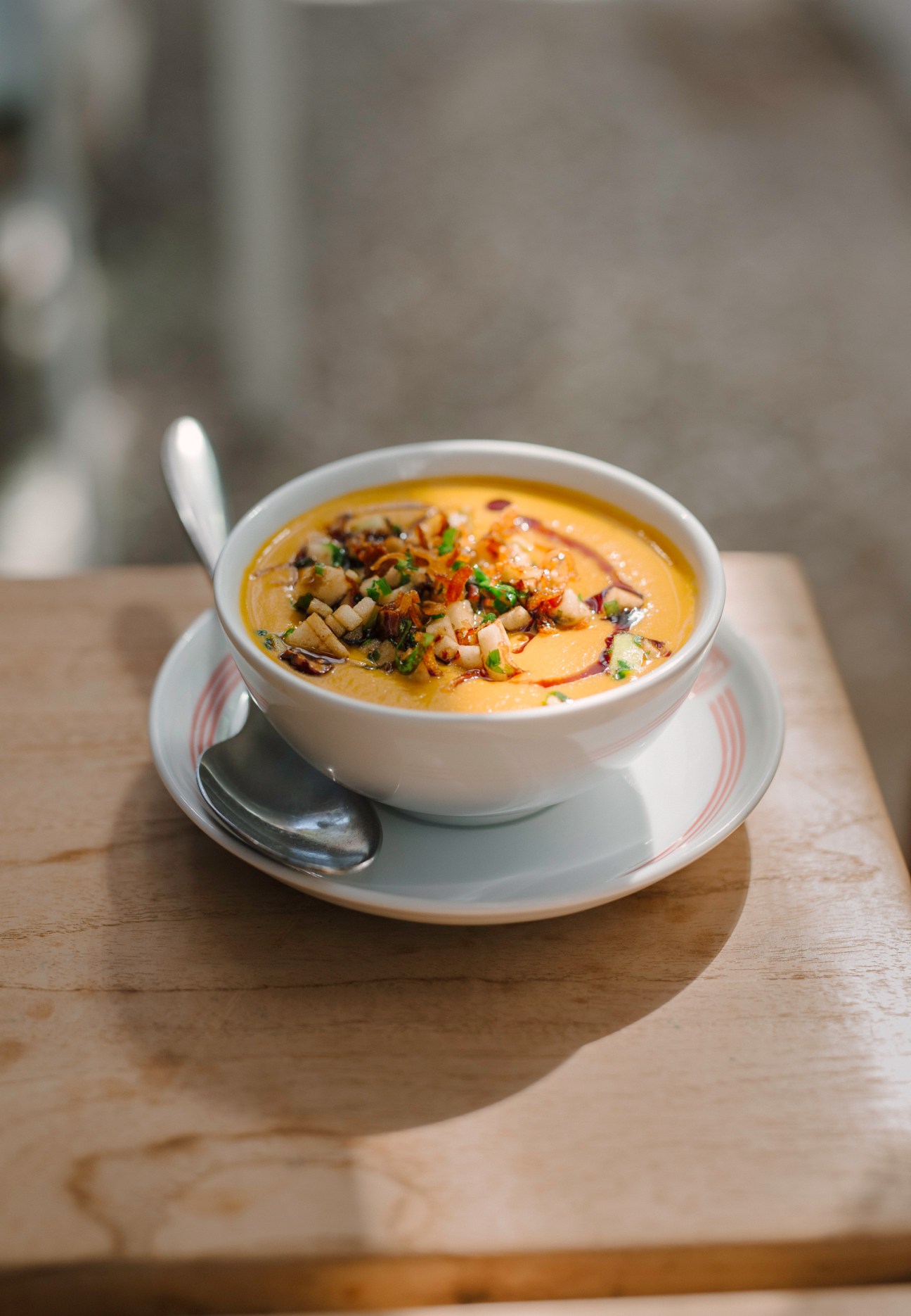 Bowl of yellow soup with mushrooms and herbs served in white bowl on wooden table