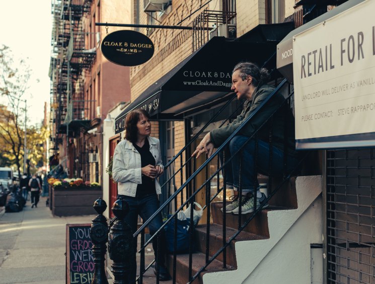 Two people having a conversation on urban steps, one sitting on stairs while the other stands nearby