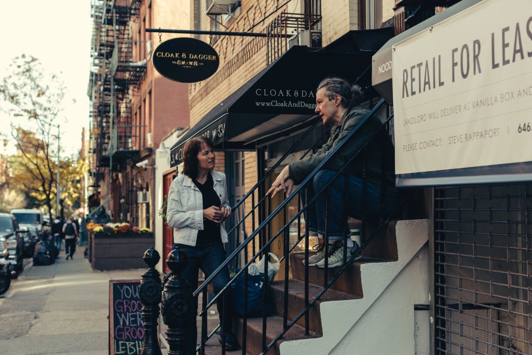 Two people having a conversation on urban steps, one sitting on stairs while the other stands nearby