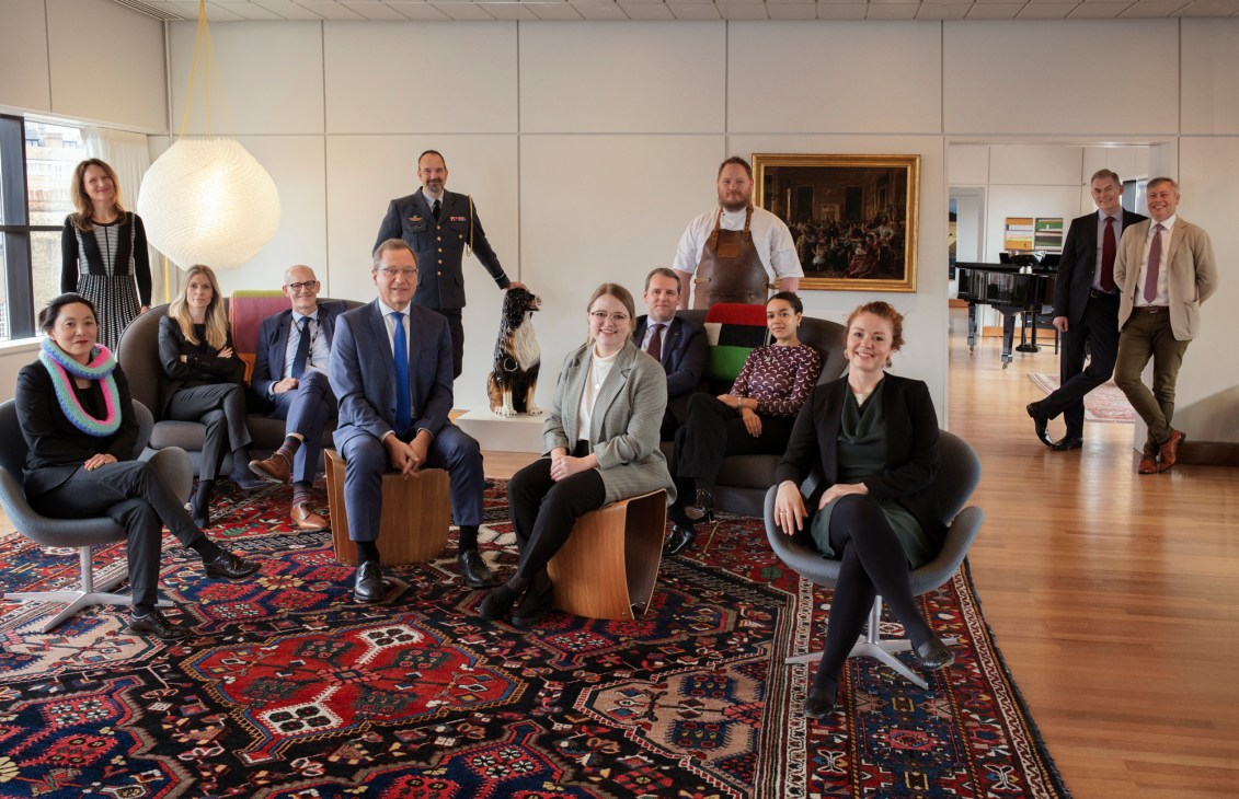 Group photo of Danish embassy staff in London seated and standing in modern office interior