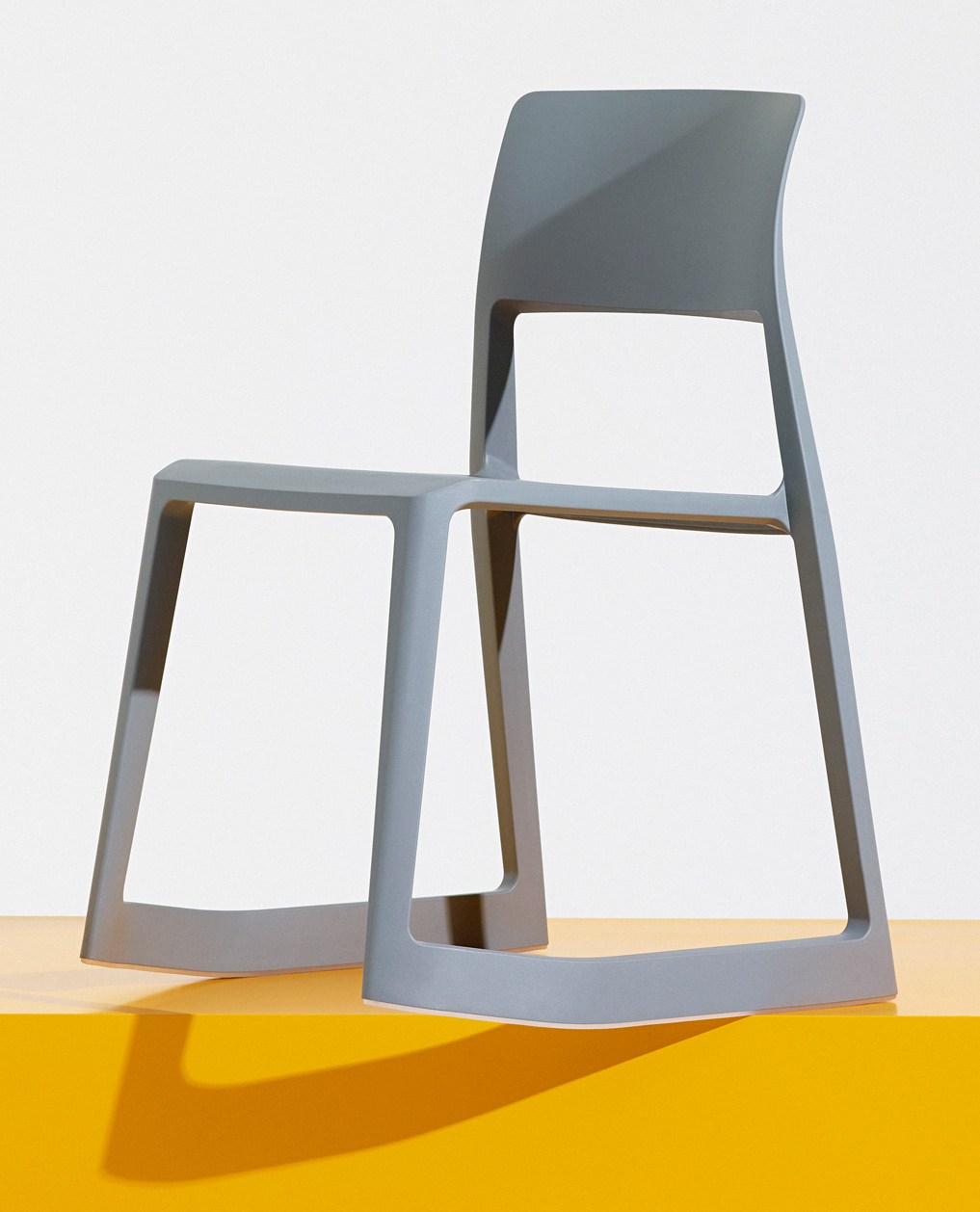 Gray molded plastic stacking chair with open frame design and curved backrest