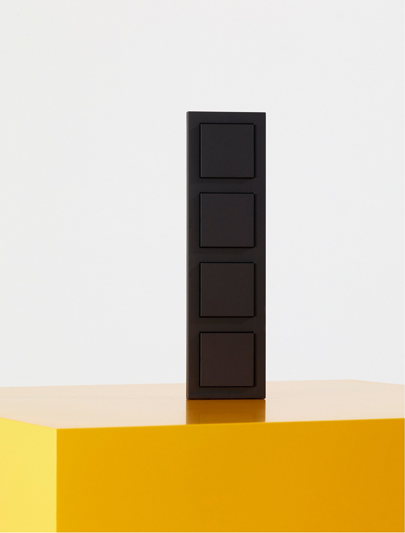 Black wall-mounted switch panel with four square buttons on a light background.