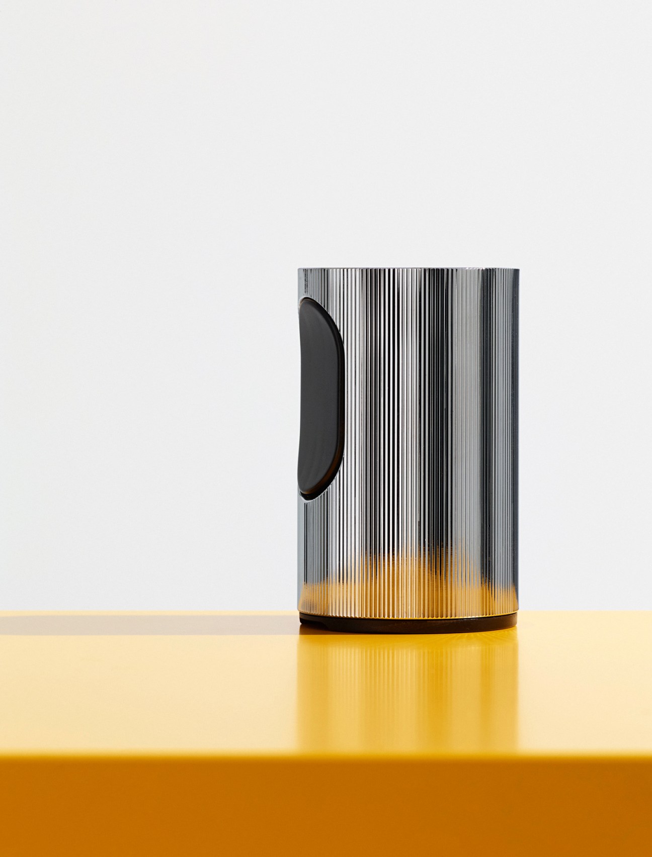Braun T2 table lighter with polished steel body and lozenge-shaped button on white background.