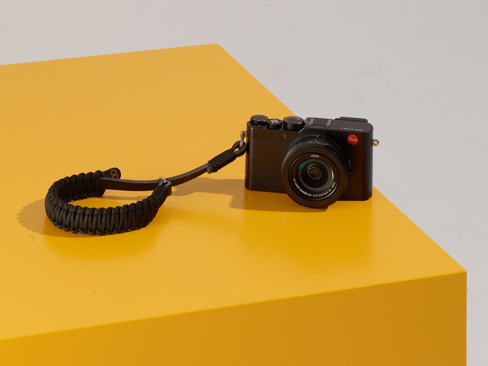 Leica D-Lux 7 camera with black paracord wrist strap on yellow surface