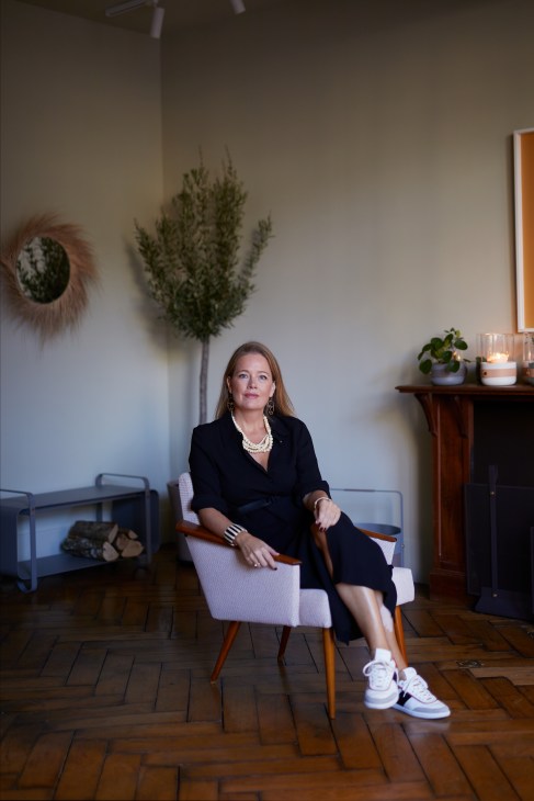 Louise Varre, founder of Eldvarm, sitting in a chair wearing a black outfit and pearl necklace