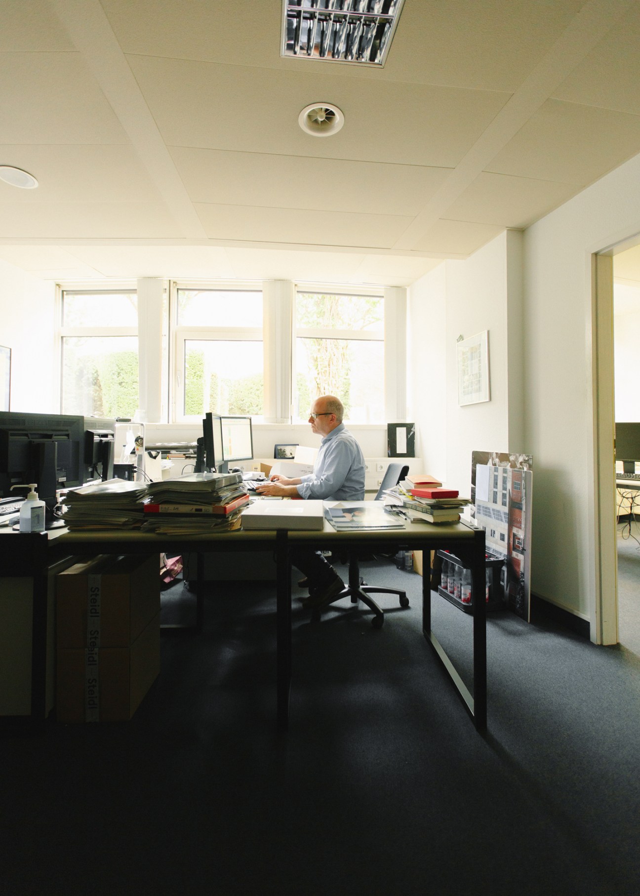 Journalist Alfons Kaiser sits at his desk working at a computer in a bright office with large windows.