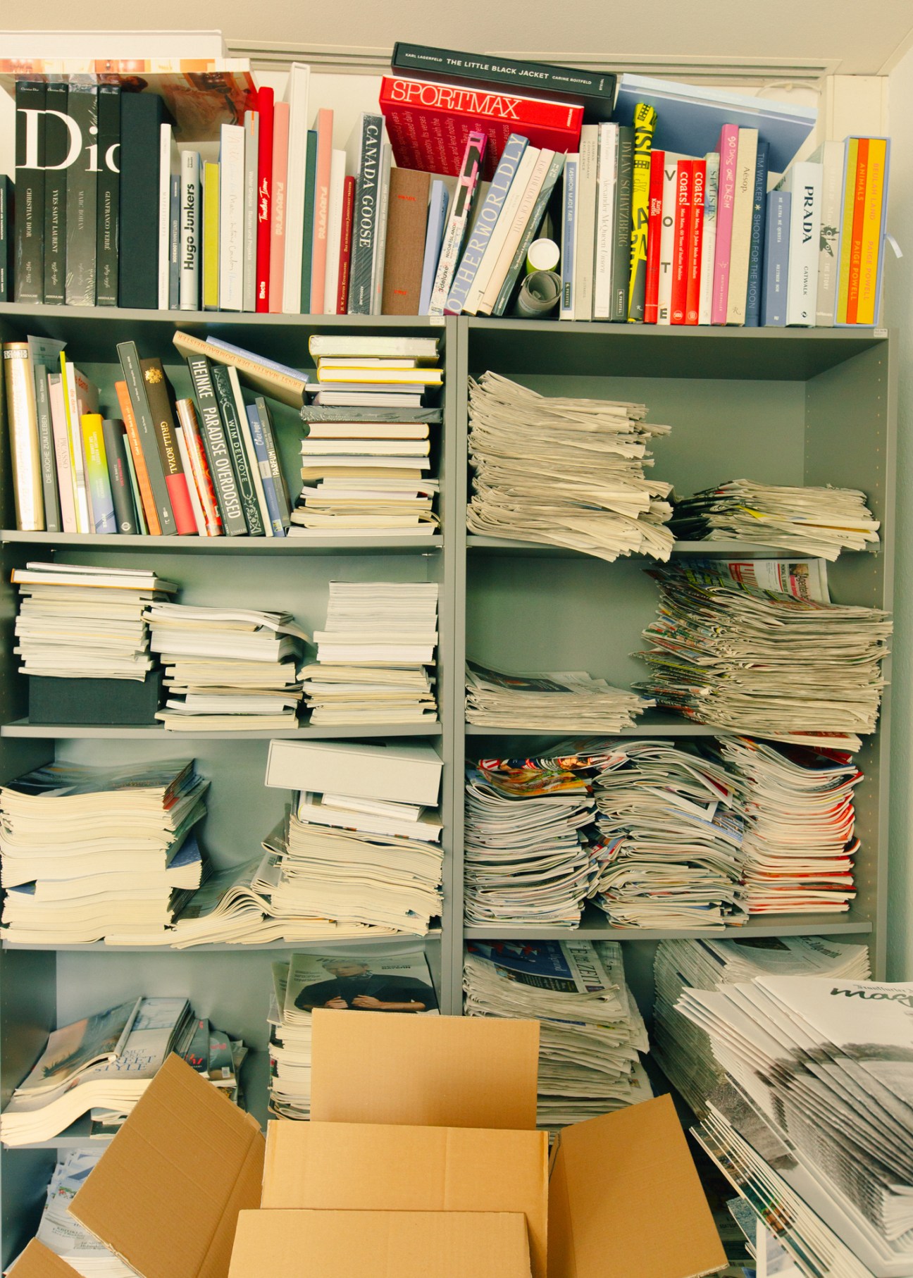 Green shelving unit filled with books, magazines, and stacked papers in journalist Alfons Kaiser's office.