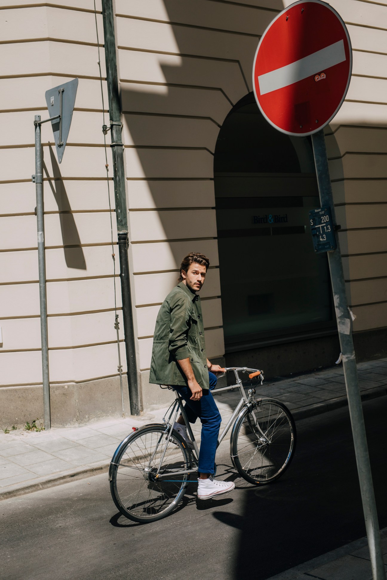 Man with bicycle standing next to red do not enter traffic sign on urban street