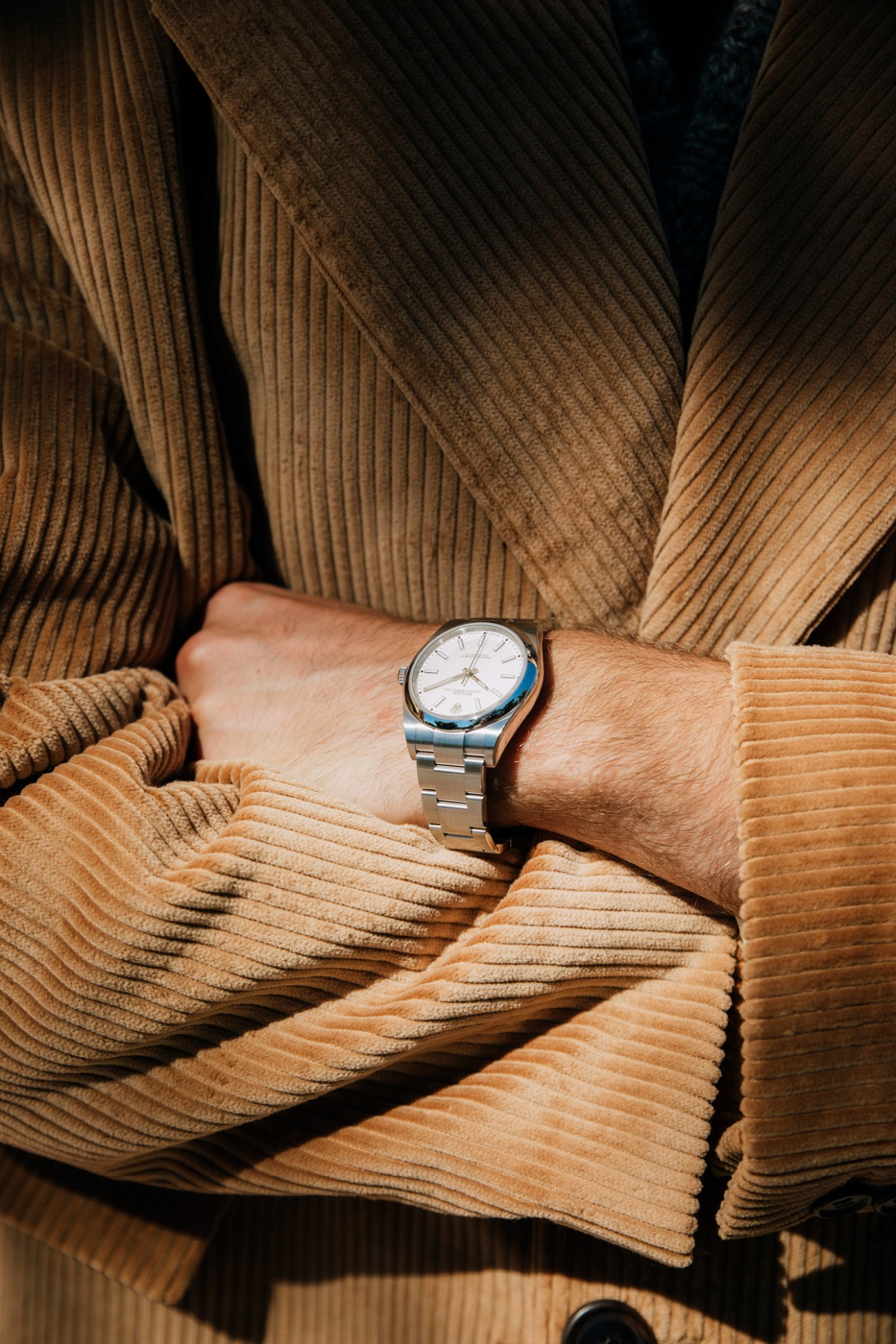 Close-up of hands wearing Prada corduroy coat and Rolex oyster perpetual 39 watch