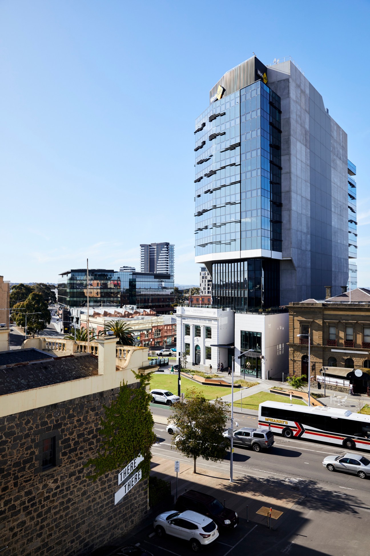 Modern multi-storey blue-glass office building with horizontal striping and white base structure in urban setting.