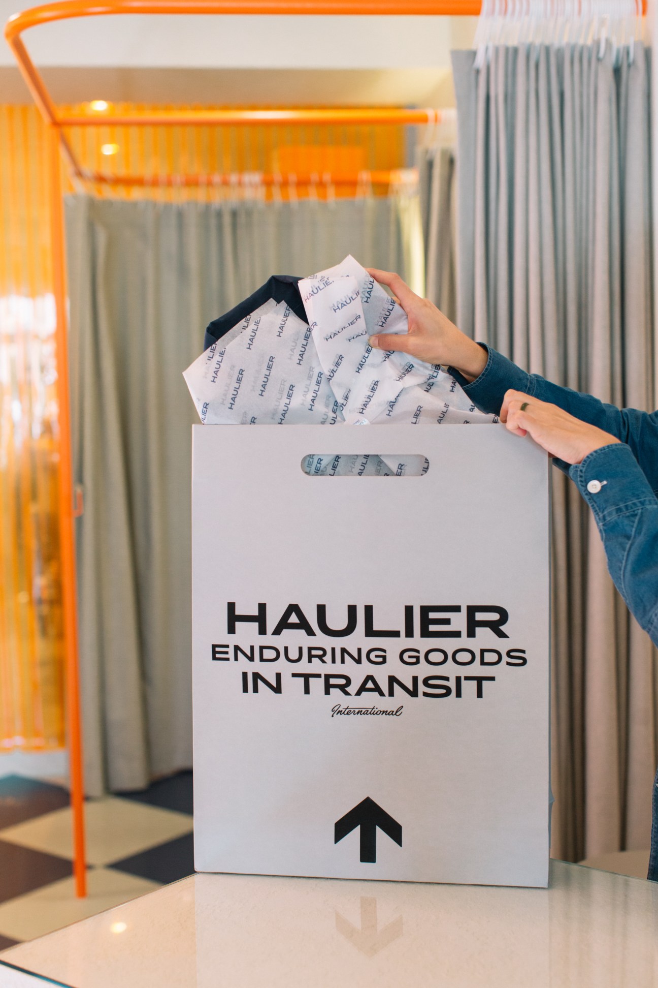 Person holding white Haulier canvas tote bag with tissue paper inside