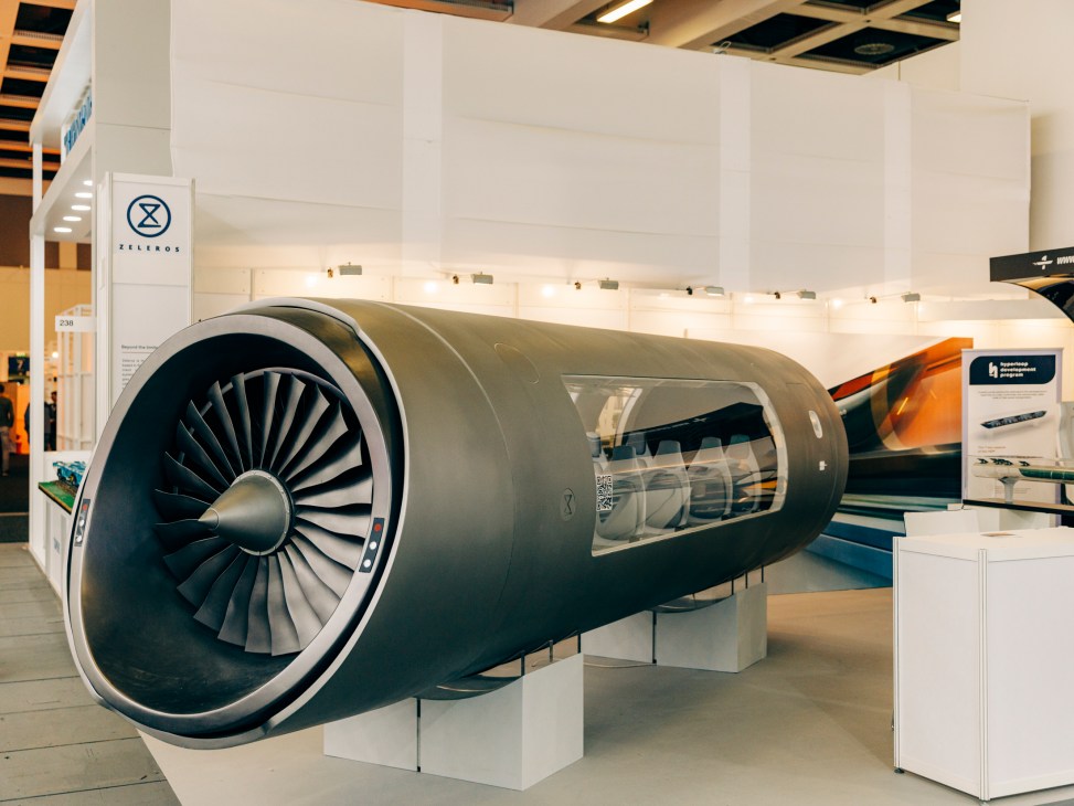 Large aircraft engine display at an exhibition with visible fan blades and cutaway section showing internal components