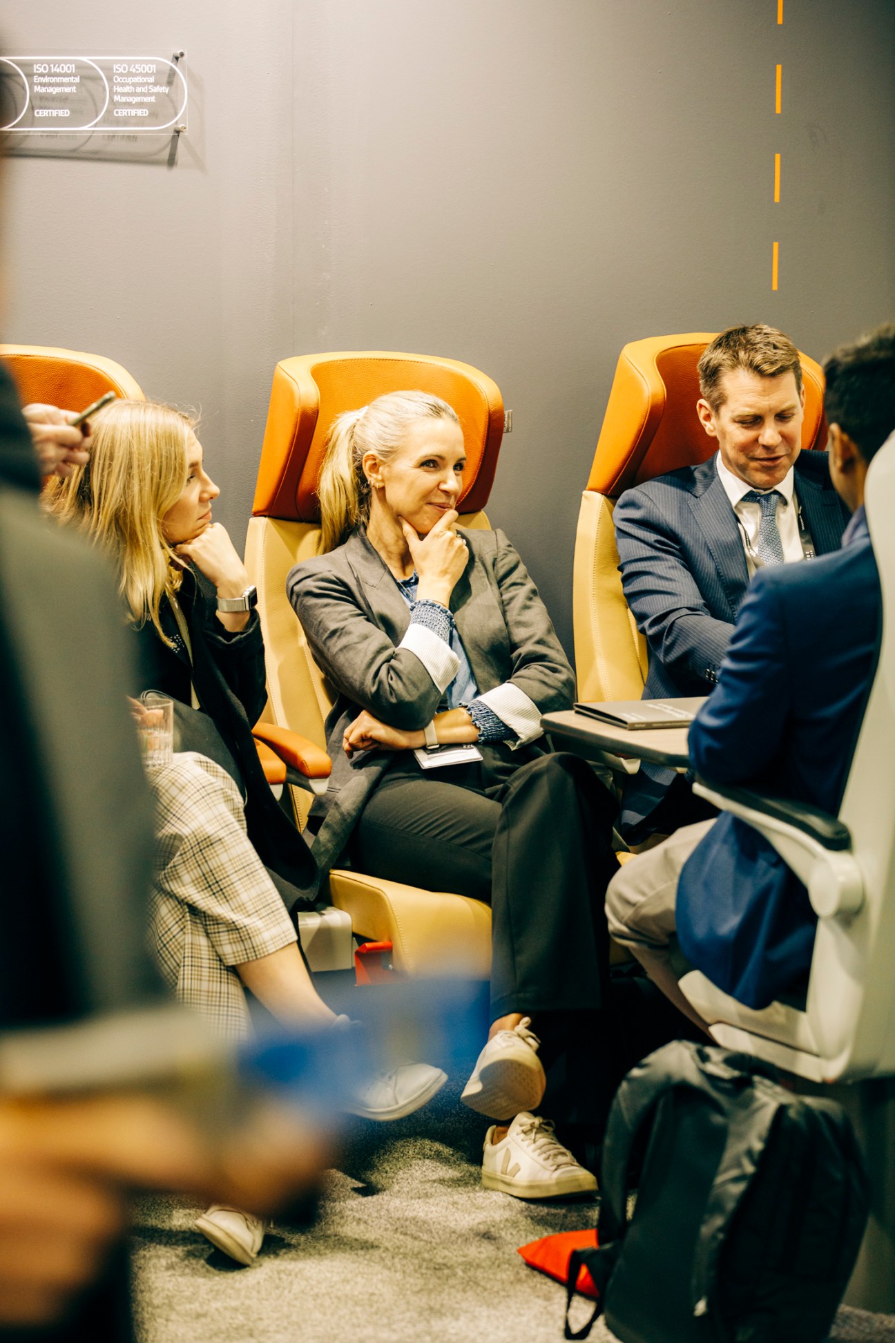 Business people in suits sitting in orange leather chairs having a conversation at a trade fair