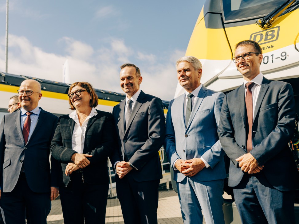 Five business executives in suits standing together at the Siemens Mobility exhibition booth at Innotrans trade fair