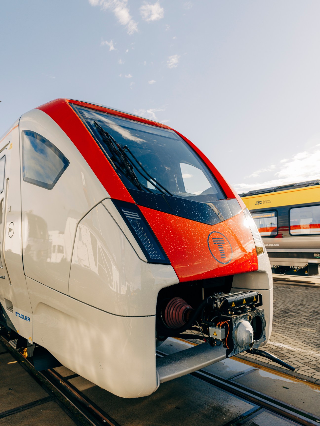 Modern white passenger train with red and blue accents displayed at indoor exhibition