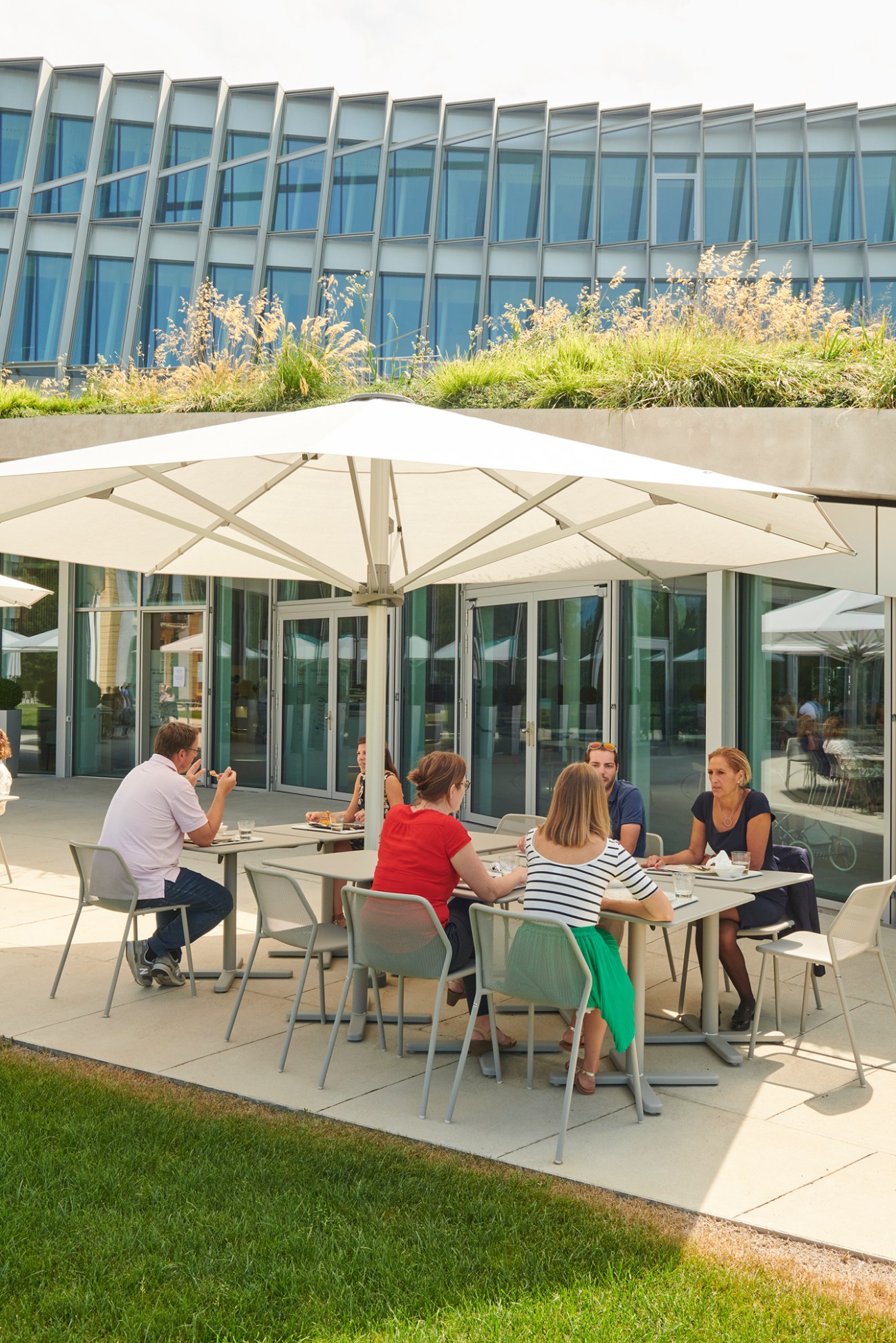 Outdoor dining area with tables and chairs under white umbrellas at the IOC headquarters