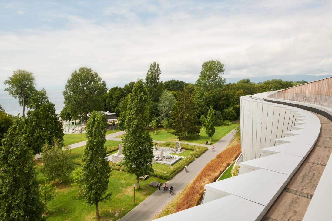 Wide exterior view of Olympic House situated in its prime lakeside location with mountains visible in the distance