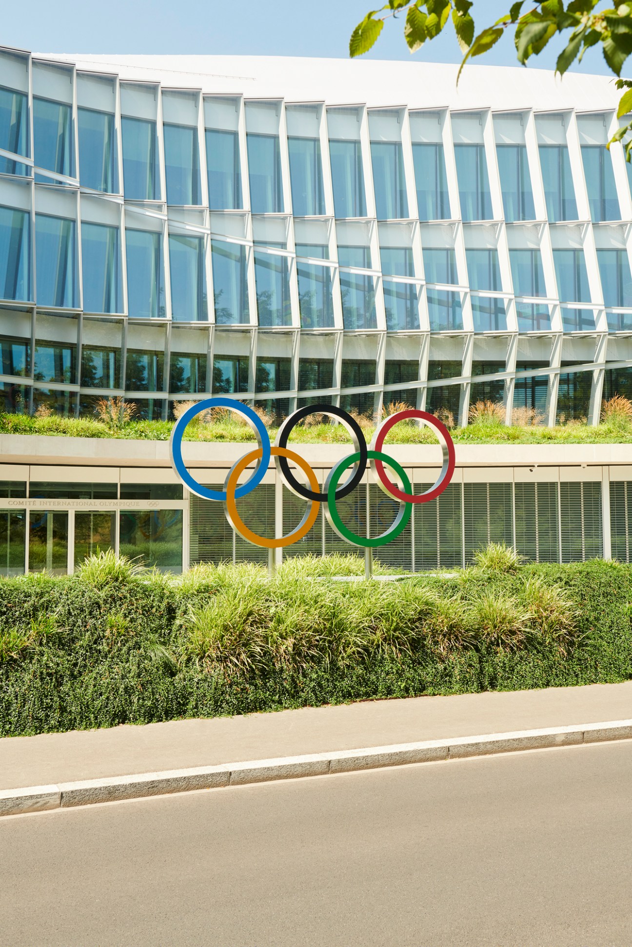 The iconic Olympic rings in blue, yellow, black, green and red displayed outside a modern glass building