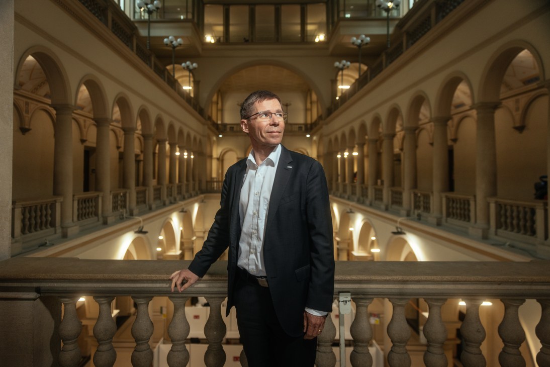 Joël Mesot, President of ETH Zürich, stands in an ornate corridor with classical architecture.