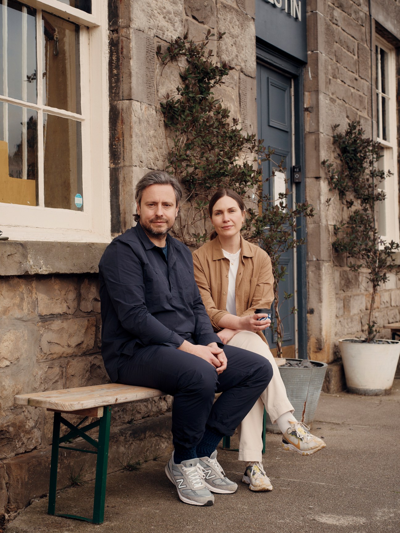 Kestin and Gemma Hare sitting together on a wooden bench outside a stone building