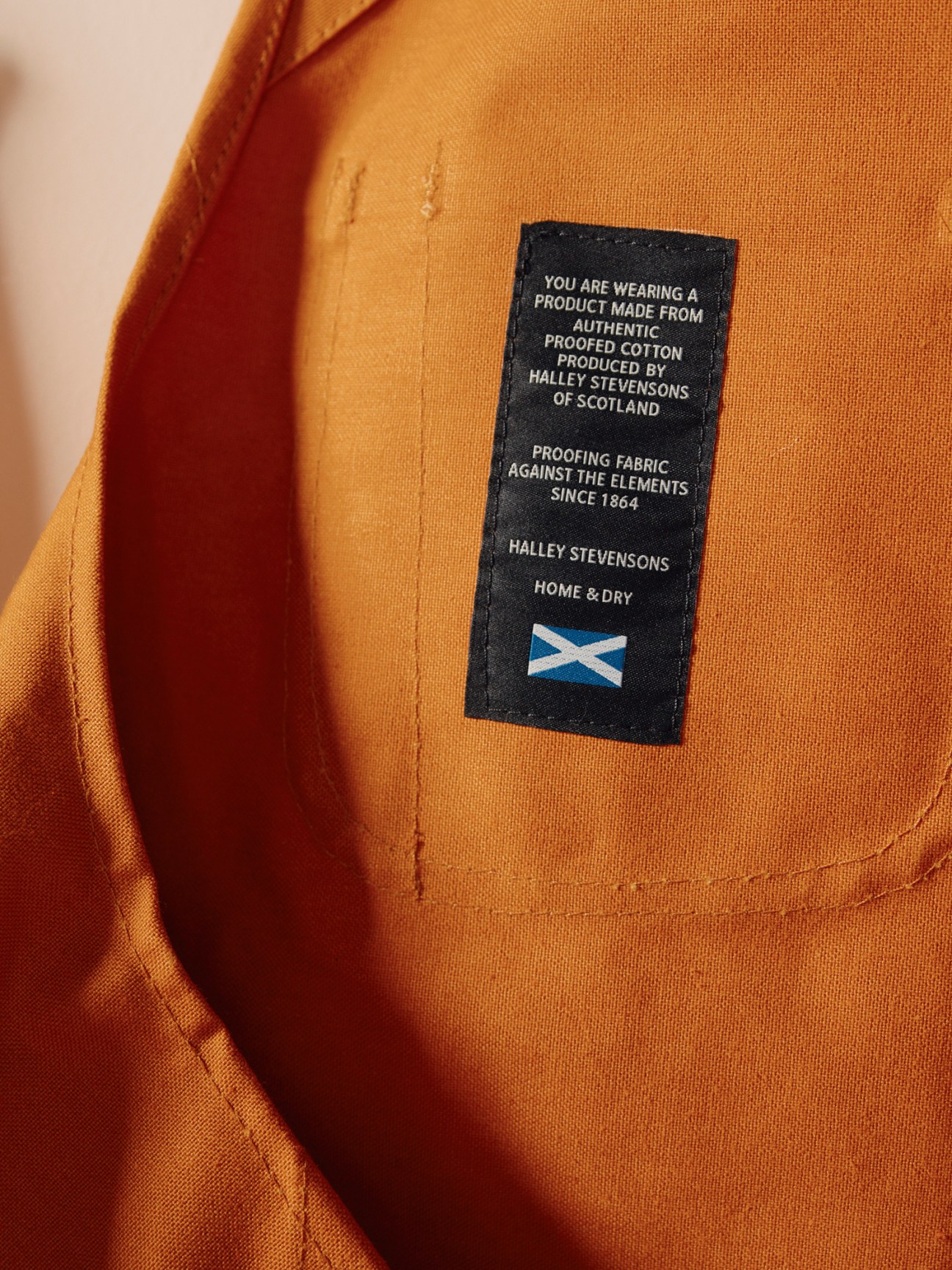 Close-up of mustard yellow garment showing Halley Stevensons fabric label with Scottish flag