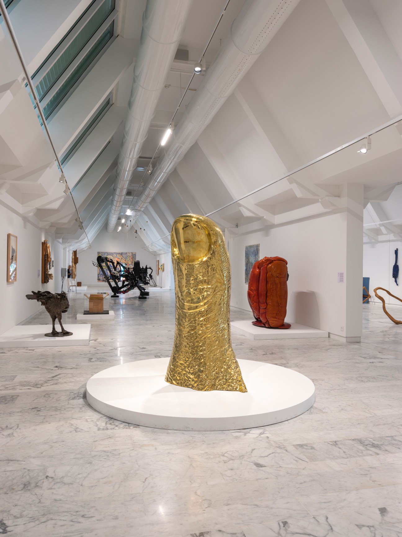Contemporary art gallery interior with gold sculptural form and colorful installations on marble floor