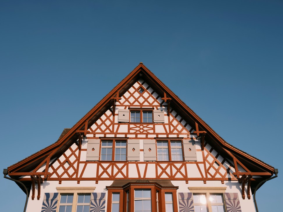 Traditional Swiss chalet with timber frame construction, red roof, and decorative wooden shutters against blue sky