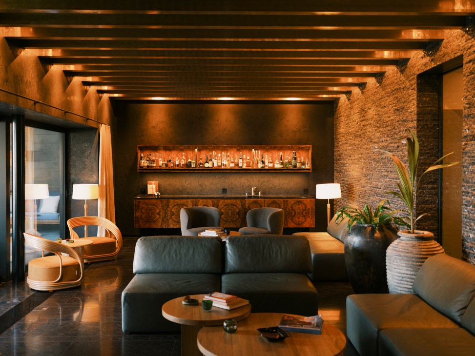 Sophisticated lounge with dark leather sectional sofa, exposed brick walls, wooden ceiling beams and built-in bar