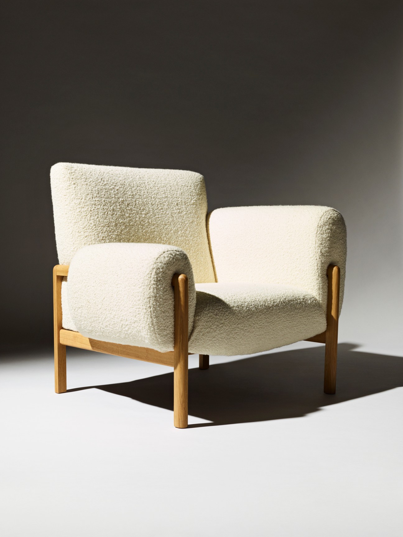 Bruno armchair with cream textured upholstery and wooden frame against gradient background